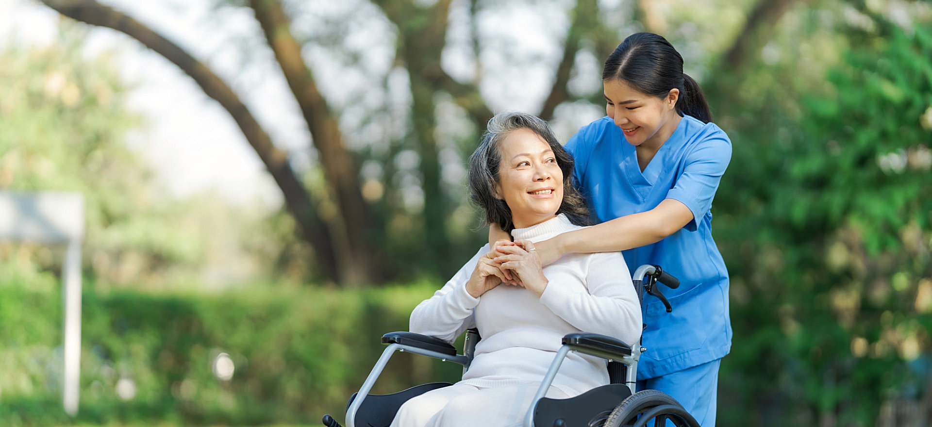 female caregiver hugging a senior woman in a wheelchair