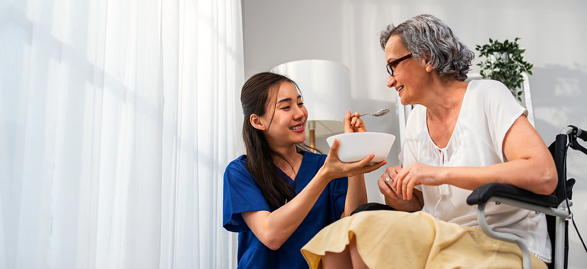 carer serving food to an elderly woman in a wheelchair